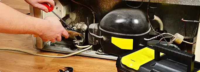 Refrigerator repair technician fixing the compressor and wiring in Ellerslie, GA