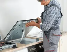 Appliance repair technician installing a built-in cooktop in Columbus, GA
