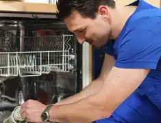 Dishwasher repair technician inspecting and servicing an open dishwasher in Columbus, GA