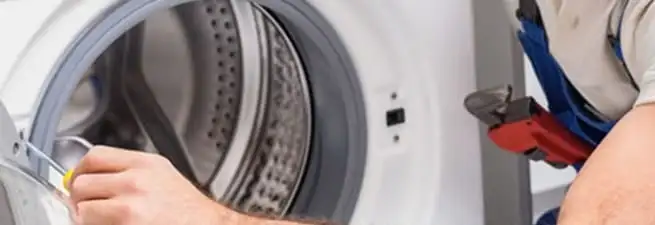 Appliance technician repairing a clothes dryer drum and internal parts in Columbus, GA