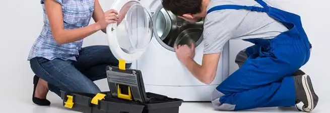 Washer repair technician inspecting a front-load washing machine with tools in Columbus, GA