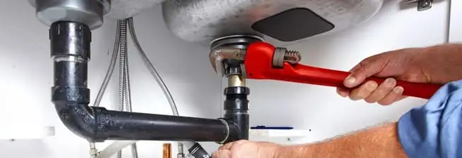 Garbage disposal repair technician tightening the sink drain and disposal connection in Columbus, GA