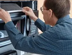 Appliance repair technician replacing a microwave vent filter in Columbus, GA