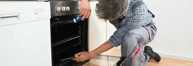 Oven repair technician inspecting and servicing an electric oven in Columbus, GA