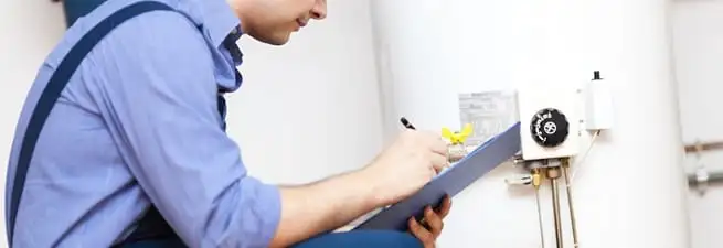Water heater repair technician inspecting the unit and recording service notes in Columbus, GA