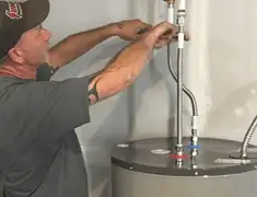 Water heater repair technician tightening supply line connections in Columbus, GA