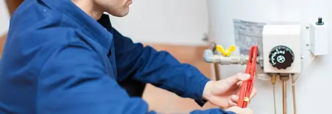 Water heater repair technician adjusting the temperature control and gas valve in Columbus, GA
